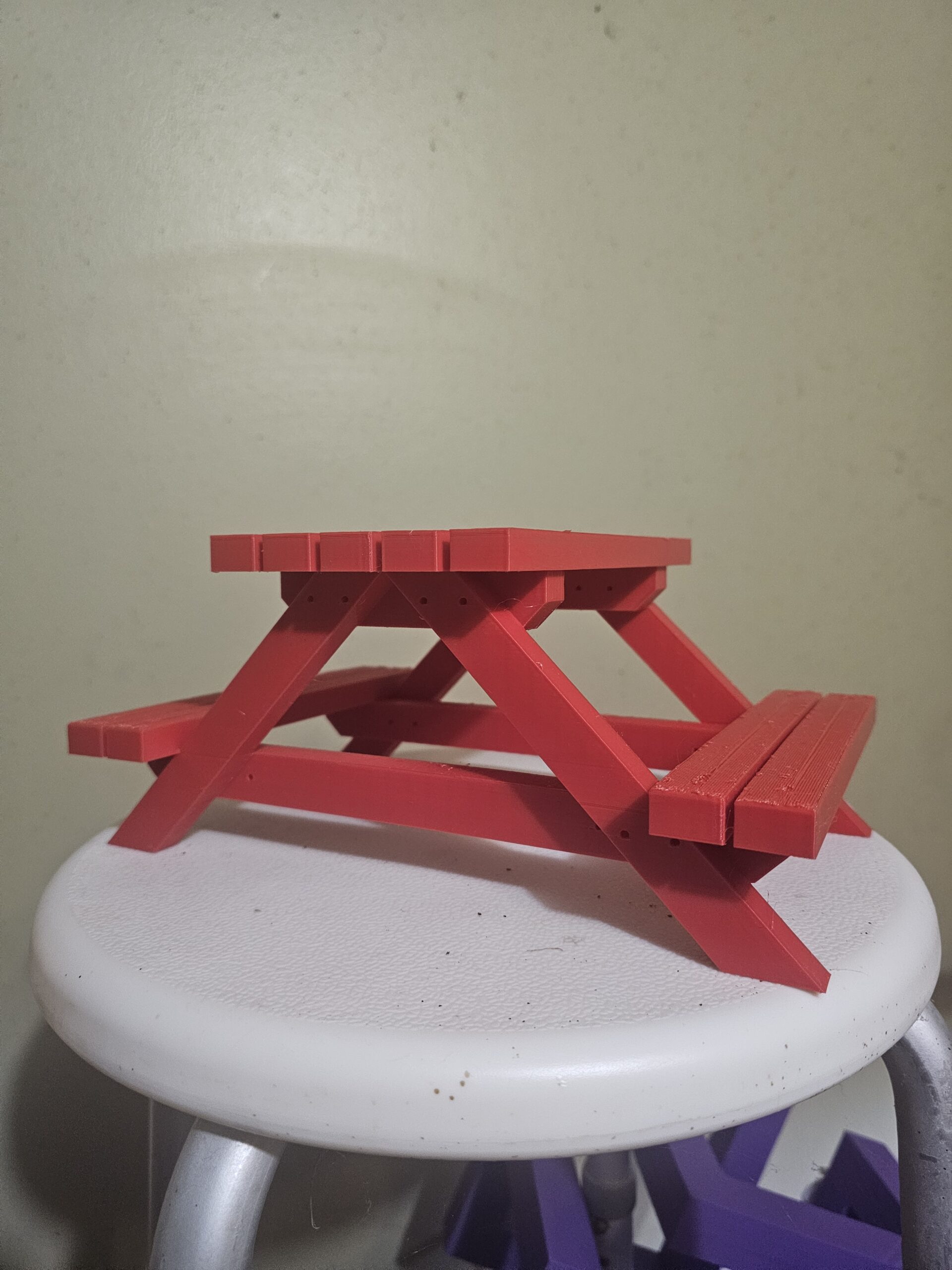 Red 3D printed mini picnic table squirrel feeder on a stool